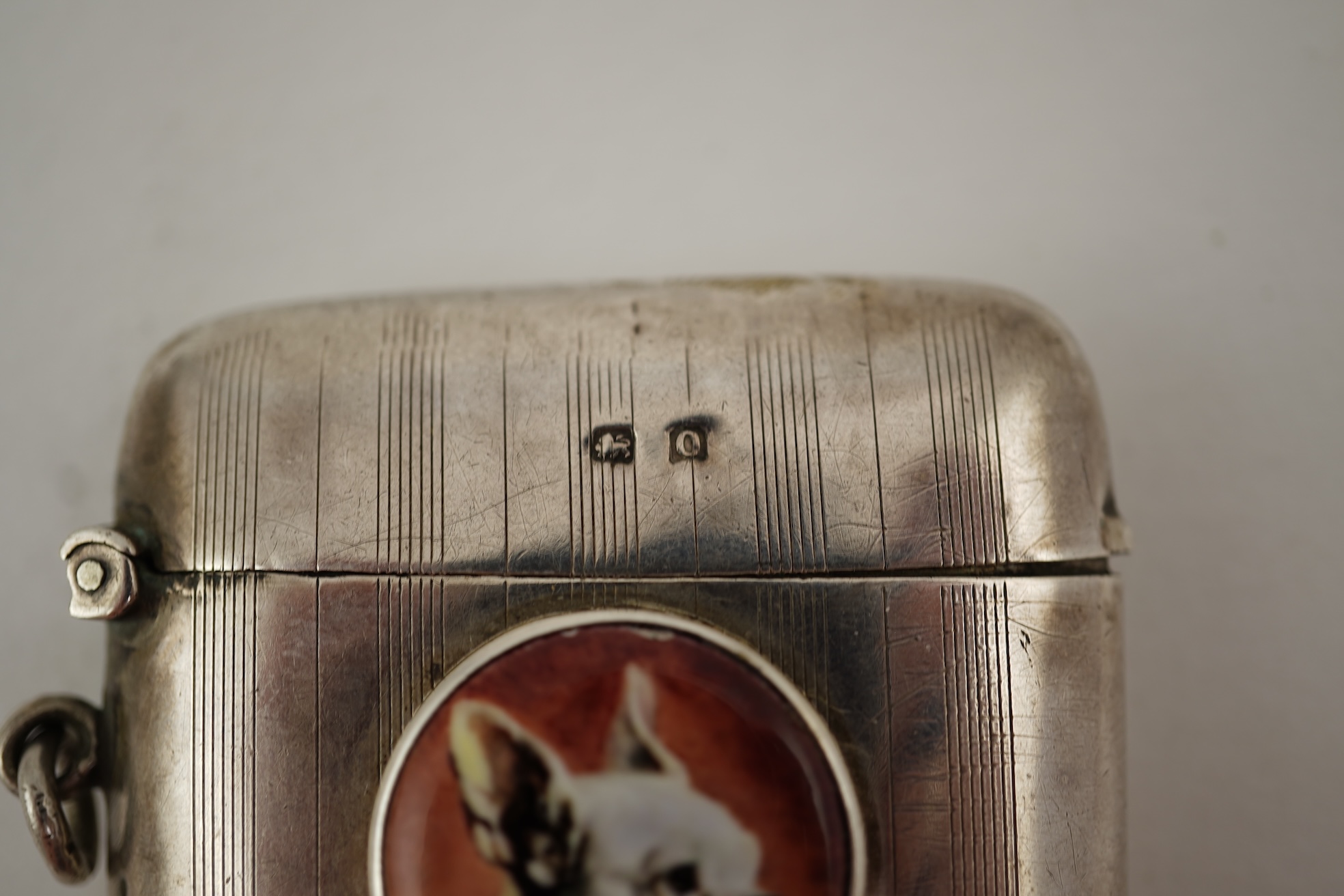 A George V silver and enamel vesta case, by Henry Hyde Aston, the inset circular enamel plaque decorated with a French bulldog